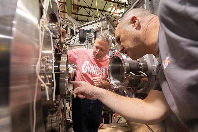 Two people look closely at a large piece of scientific equipment