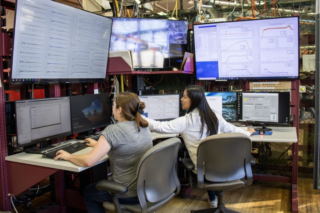 two people sitting in a lab in front of computer monitors