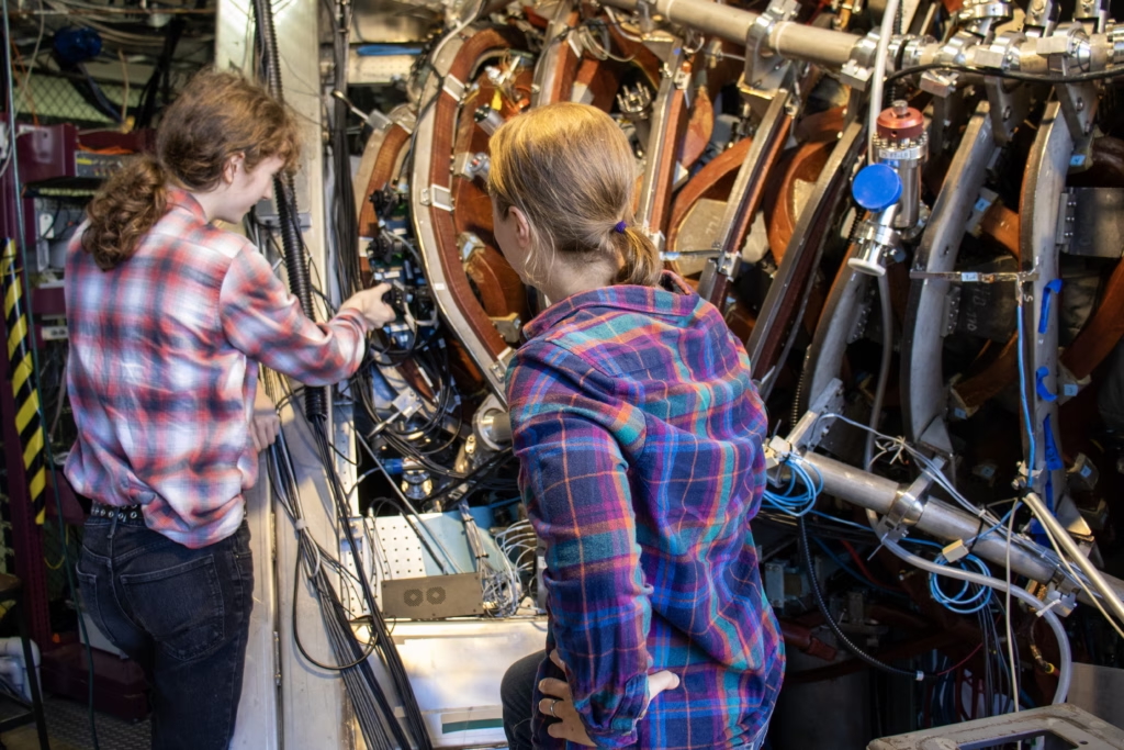 two people working closely on a large piece of scientific equpiment