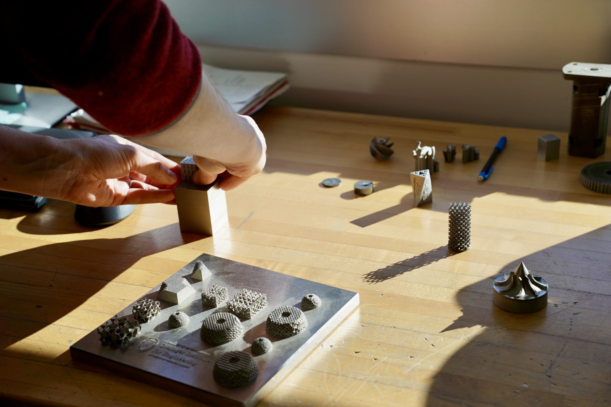 hands interacting with small, 3D printed metal components
