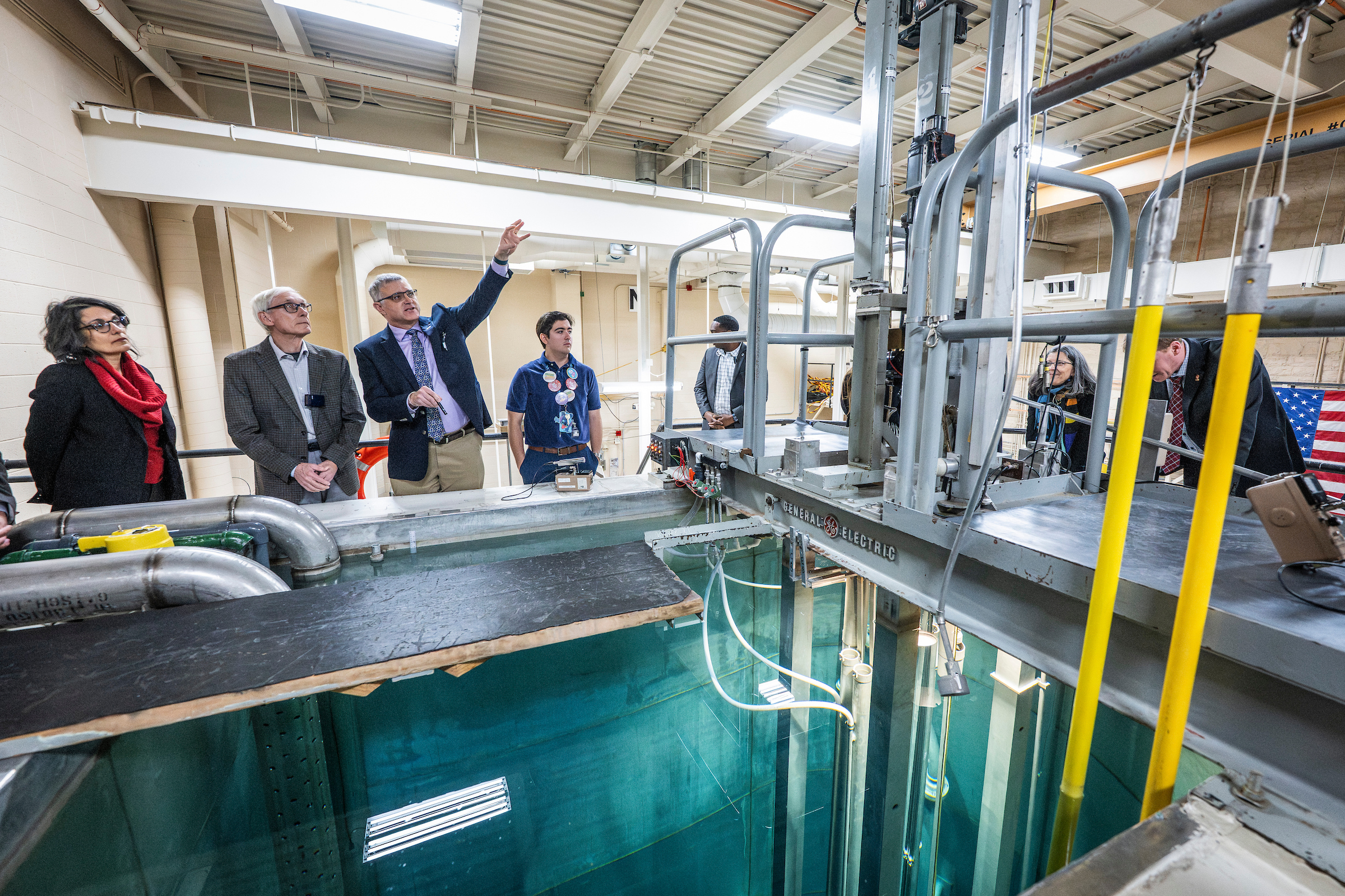 seven people standing in front of a nuclear pool with piping and a ladder