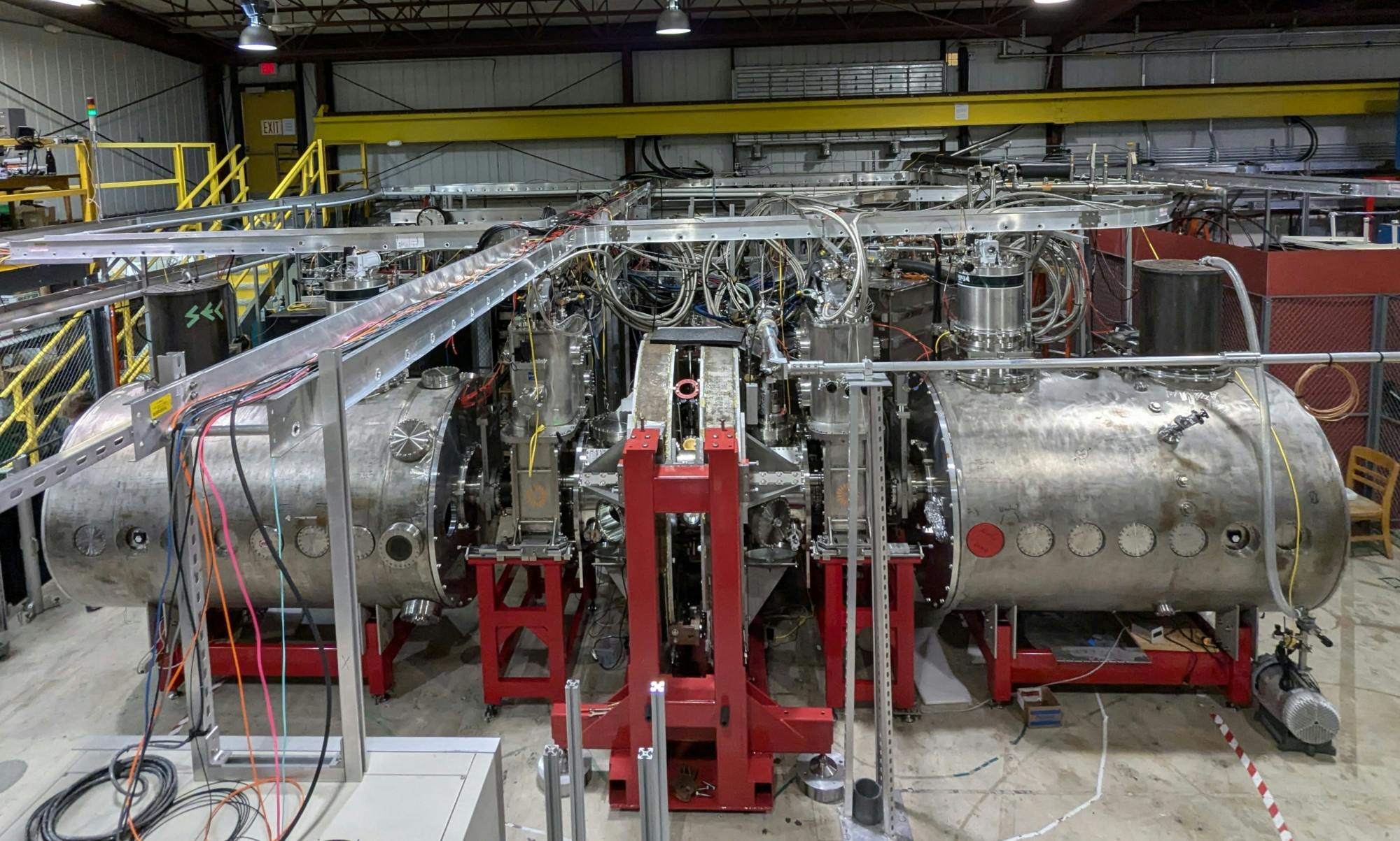 warehouse with large piece of cylindrical fusion science equipment that is silver and red in color