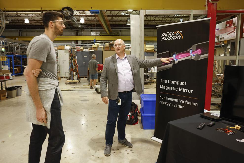 two men stand in front of an informational poster about Realta Fusion