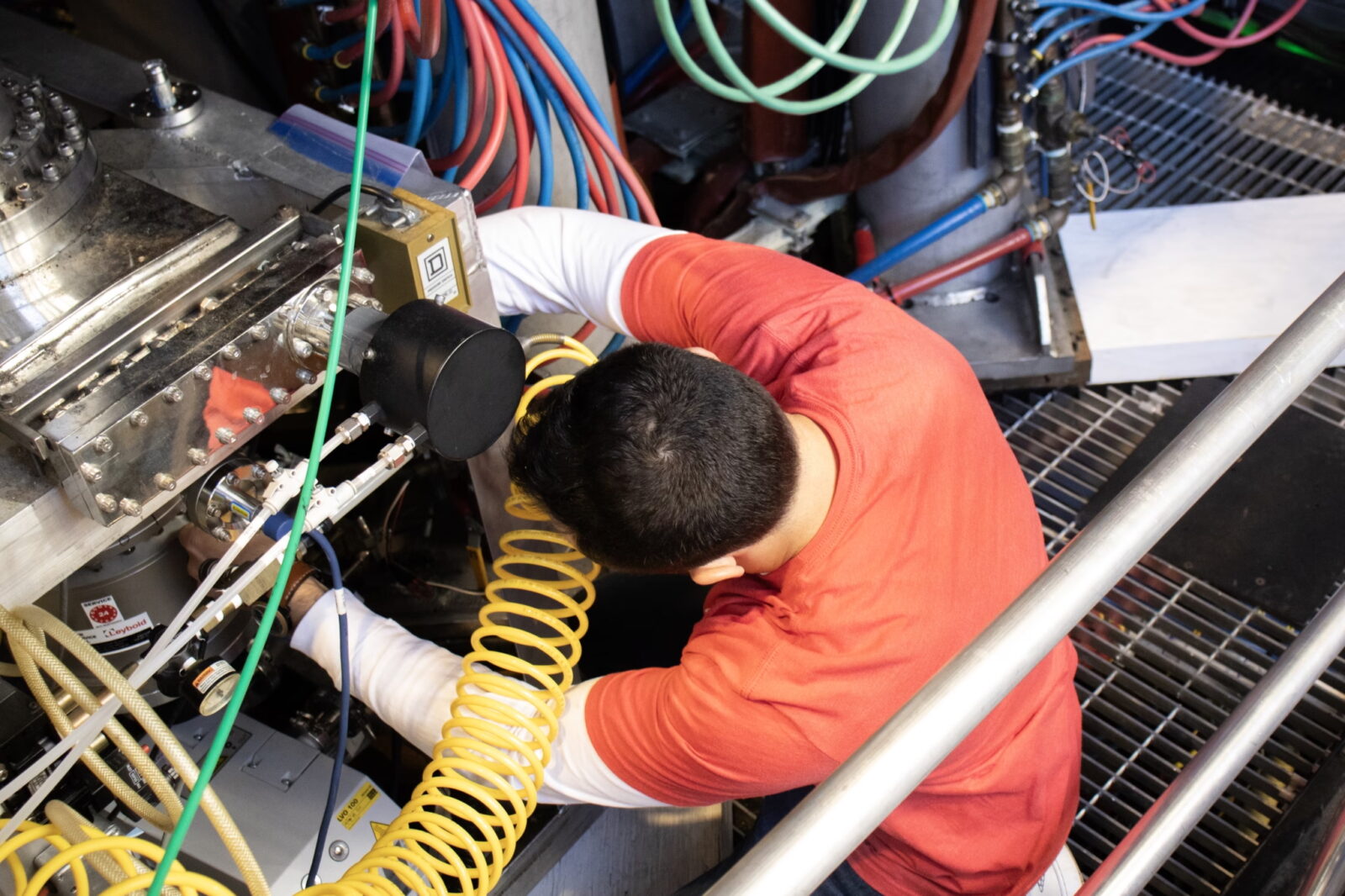 person bending down to work on a piece of scientific equipment