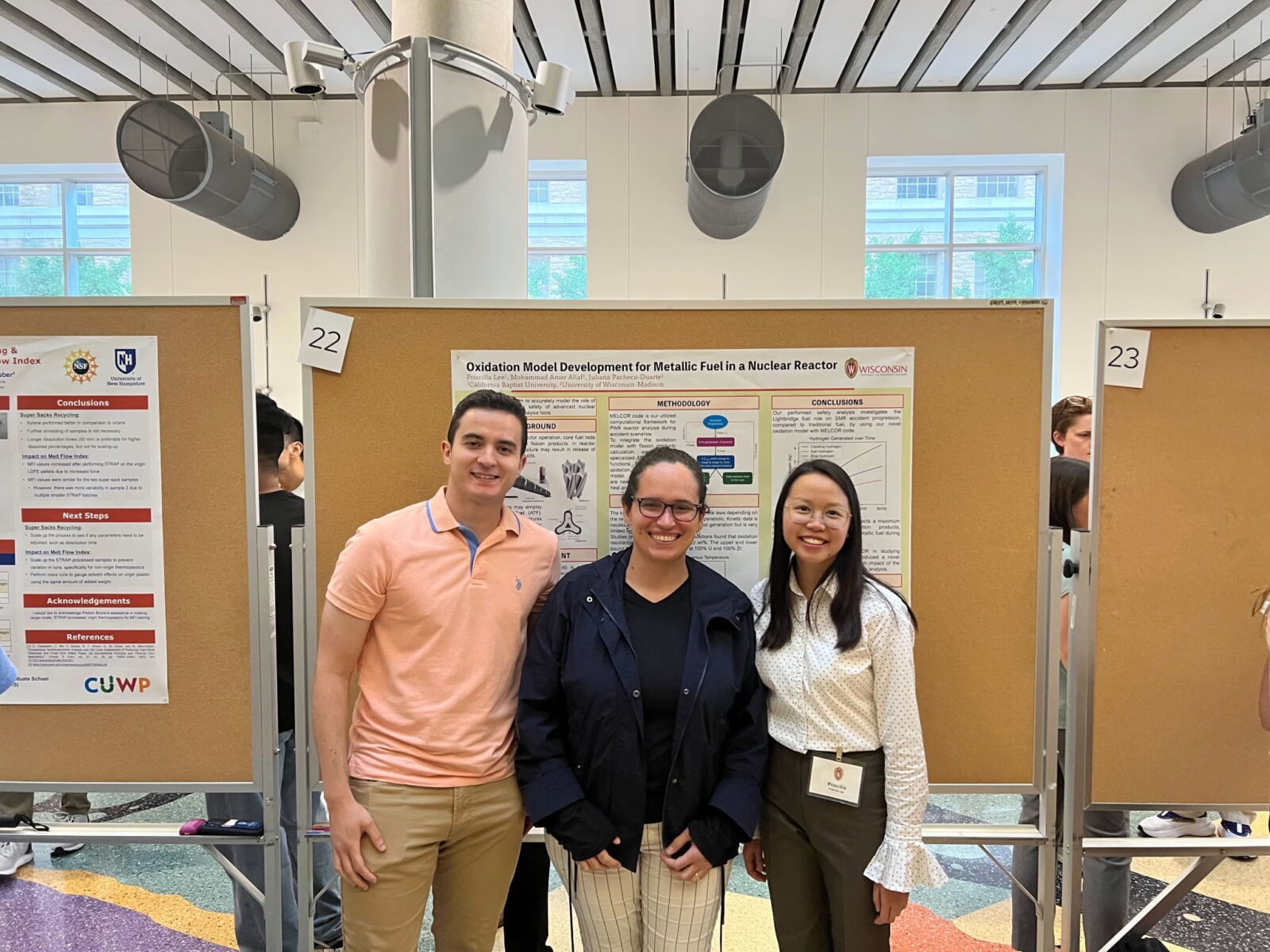 three people stand in front of a scientific poster